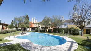 A swimming pool with a curved edge, surrounded by a well-maintained lawn and trees. - Los Jandalos in El Puerto de Santa Maria (El Puerto de Santa Maria)