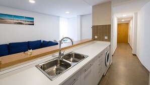 Una cocina moderna con un lavamanos doble, encimera de madera y una lavadora.