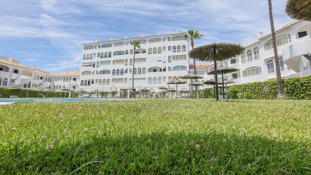 Et hotel med swimmingpool, grøn græsplæne og hvide bygninger med flere altaner.