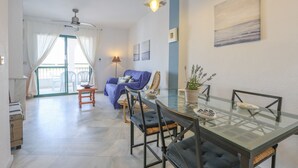 Spiseområde med et glasbord og stole, en loftsvifte og udsigt til balkon.