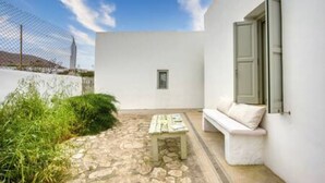 A white building with a stone patio, a bench, and a small table.
