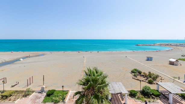 A beach with a clear sky, a sandy shore, and a few people. - Marina De La Duquesa 805 (Manilva)