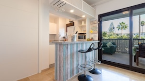 A kitchen with a bar area, a microwave, and a view of the outdoors. - Marina De La Duquesa 805 (Manilva)