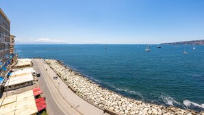 A coastal road with a rocky breakwater, a clear blue sea, and several boats. - Blu Breeze on Seafront (Naples)