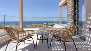 Un balcone con sedie in vimini e un tavolino, vista sulla costa.
