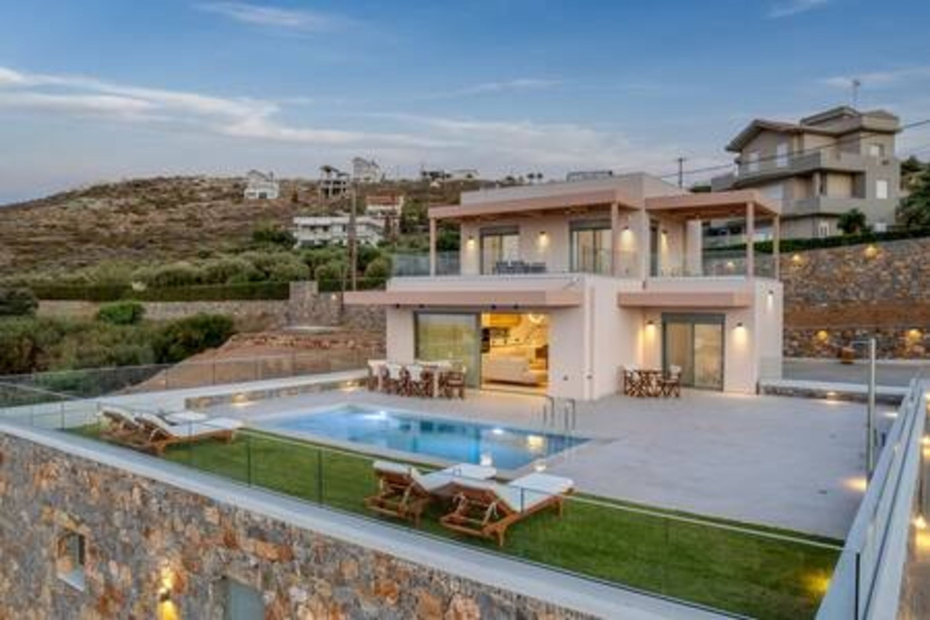Una casa moderna con piscina, area relax esterna e vista sul paesaggio circostante.