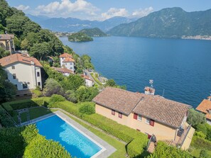 A residential area with a swimming pool, houses with red-tiled roofs, and a lake with mountains in the background. - Casa Vela in Sala Comacina (Sala Comacina)