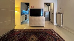 A modern kitchen with a flat-screen TV, a refrigerator, and a patterned rug. - [Historic House] in the Heart of Bergamo (Bergamo)