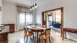 A dining area with a round table, four chairs, and a wooden bench. There is a mirror on the wall and a blue sofa in the background. - Spacious Apartment Near Saint Peter's Basilica
 (Roma)