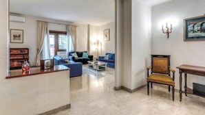 A spacious living room with a blue sofa set, a wooden chair, and a coffee table. - Spacious Apartment Near Saint Peter's Basilica
 (Roma)