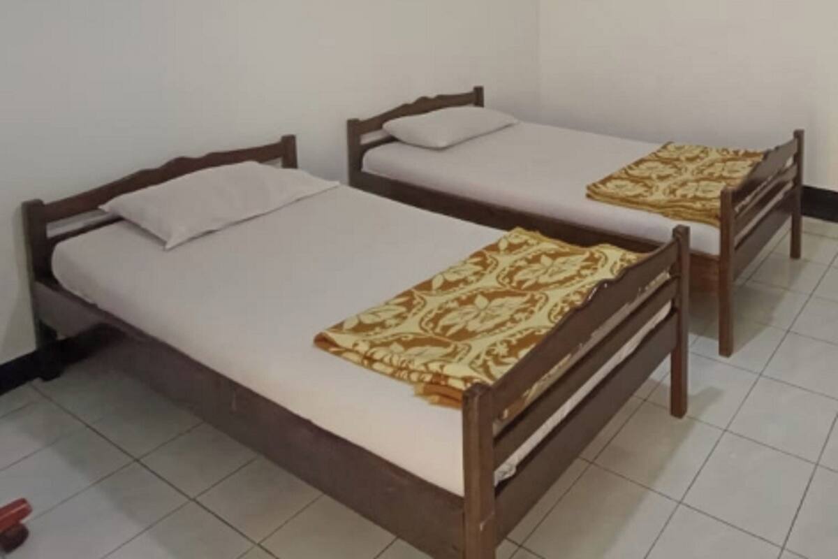 Una stanza con due letti di legno, ognuno con un materasso bianco e una coperta a motivi.