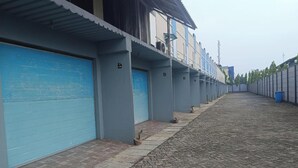 Fila de portes de garatge blaves amb indicadors numèrics, un passeig pavimentat i un cubell de brossa blau.
