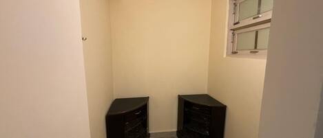 A narrow hallway with two dark-colored cabinets, a patterned floor, and a window with blinds.