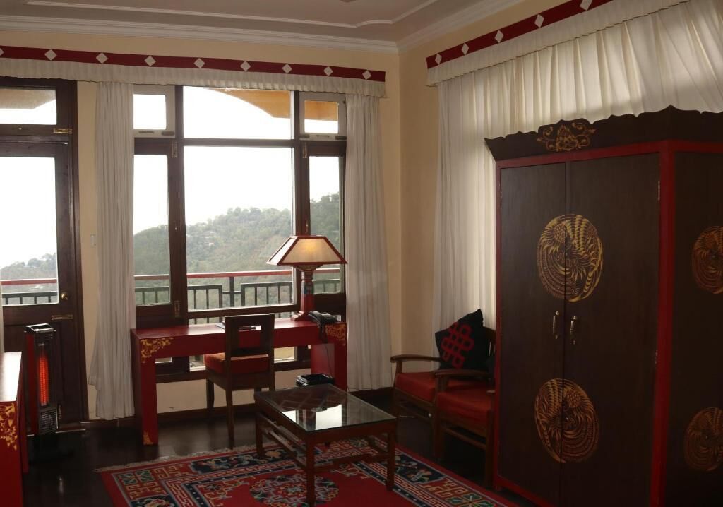 Una habitación tradicional con un mueble de madera grande, una mesa, sillas y vistas a un paisaje montañoso a través de amplios ventanales.