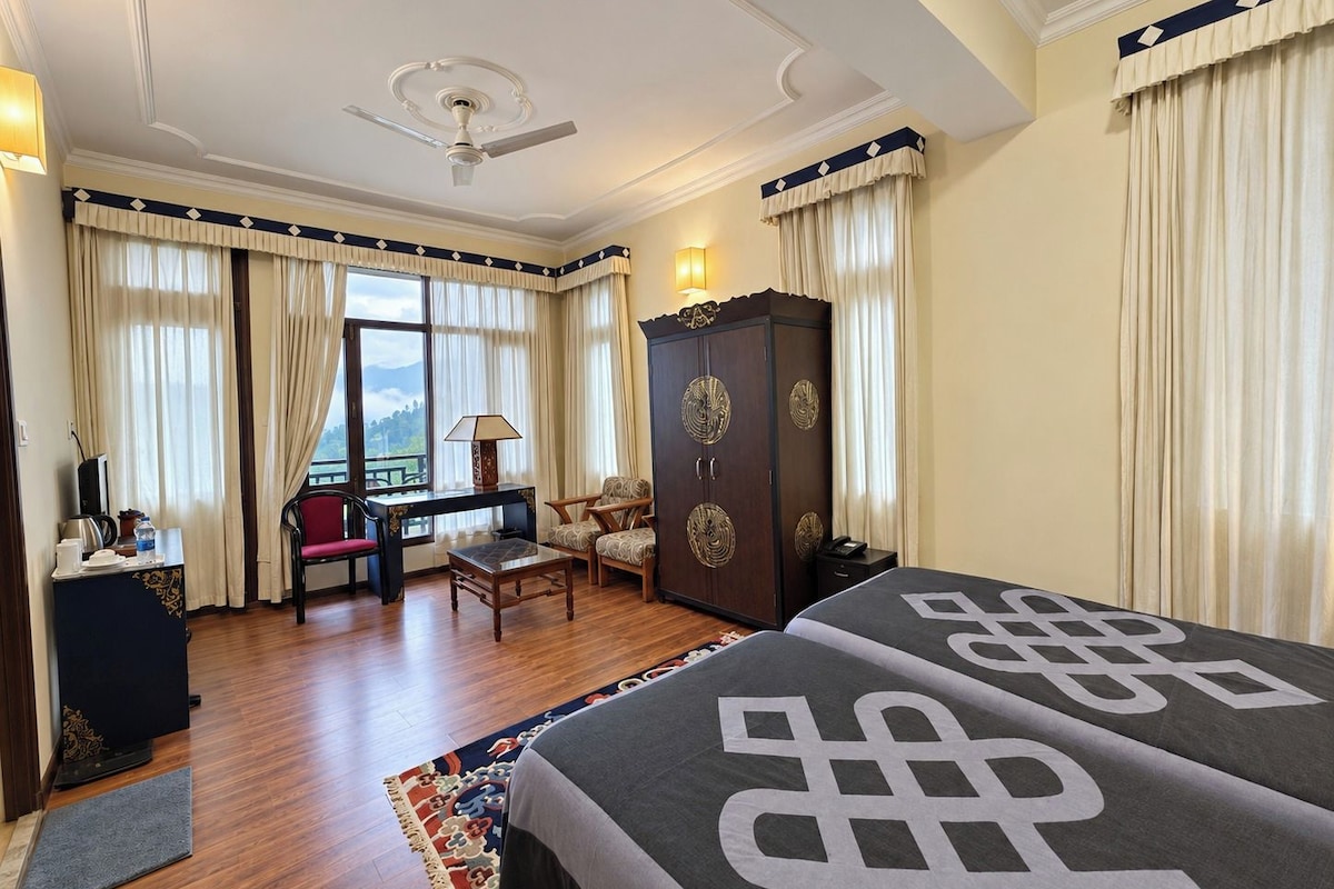 A hotel room with a bed, a desk, a chair, a wardrobe, and a view of the outdoors.