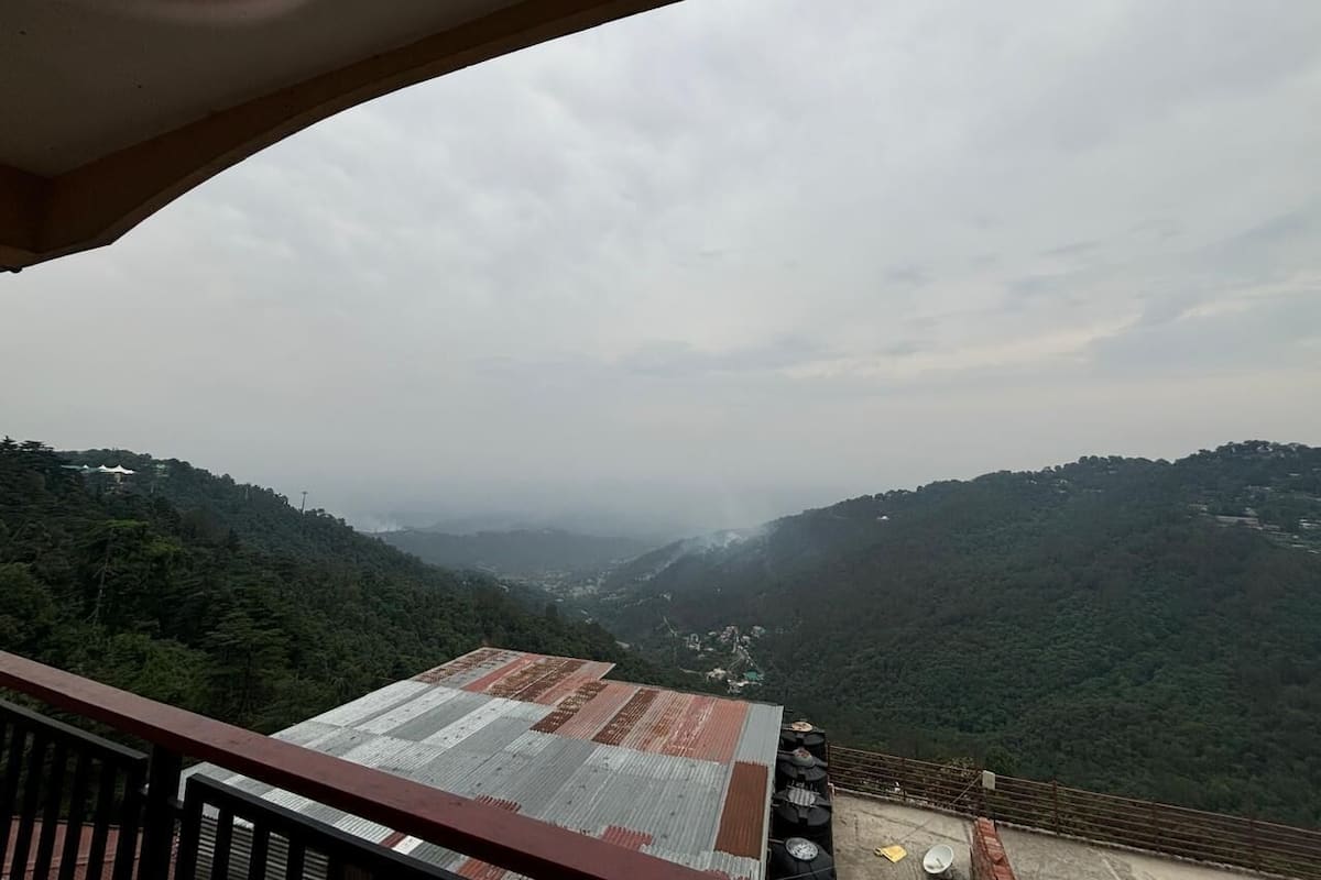 Vista desde un balcón sobre un valle con colinas boscosas.