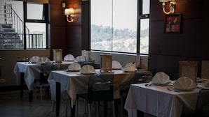 Un ristorante con tavoli apparecchiati per la cena, ampie finestre con vista e illuminazione a parete.