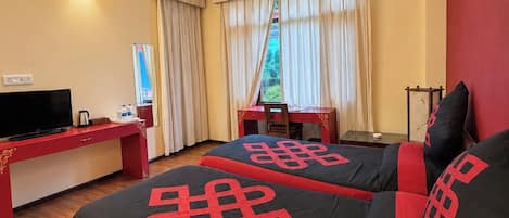 Una camera d'albergo con due letti, una scrivania, un televisore e una ventola a soffitto.