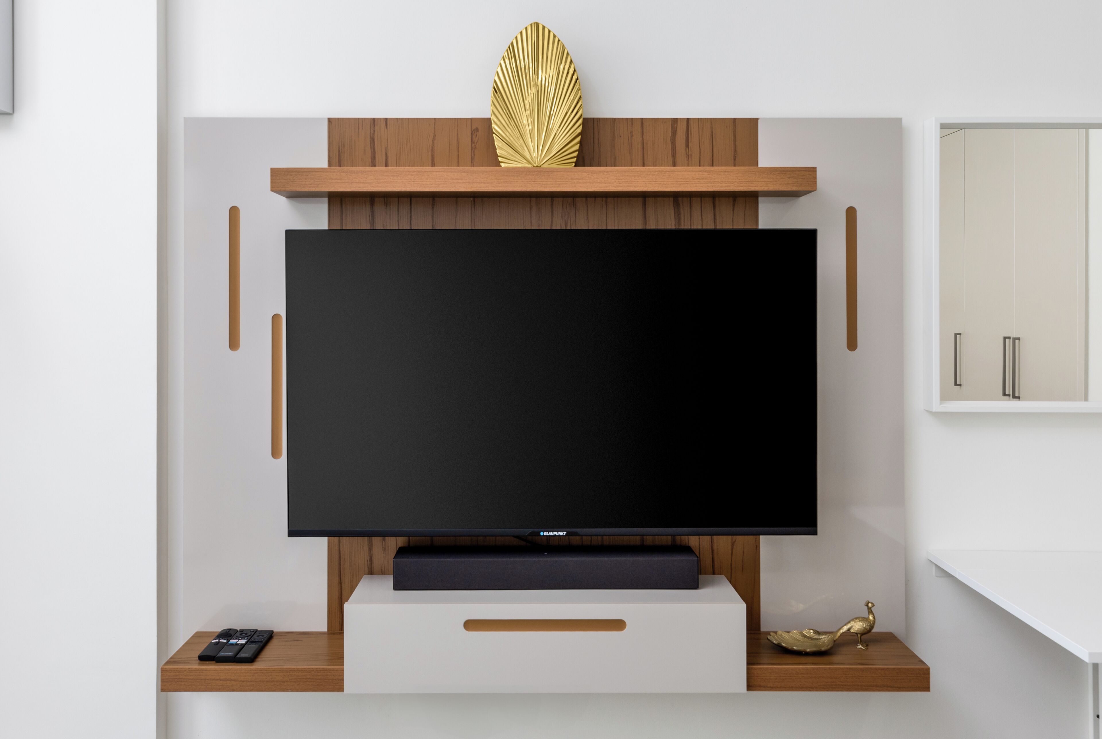 Un meuble de divertissement moderne doté d’un téléviseur à écran plat, d’étagères en bois et d’objets décoratifs.