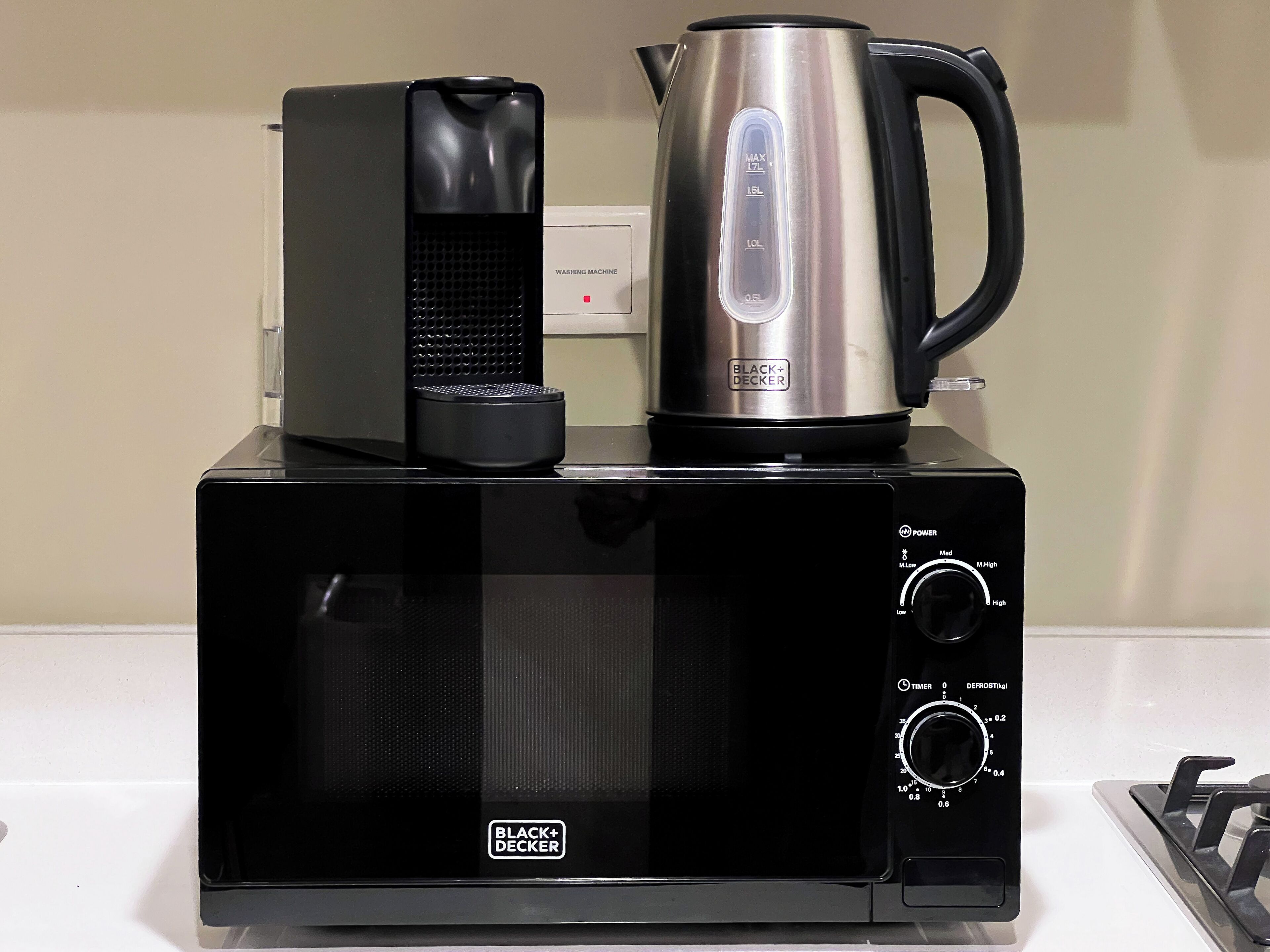 A BLACK+DECKER microwave with a kettle and toaster on top.
