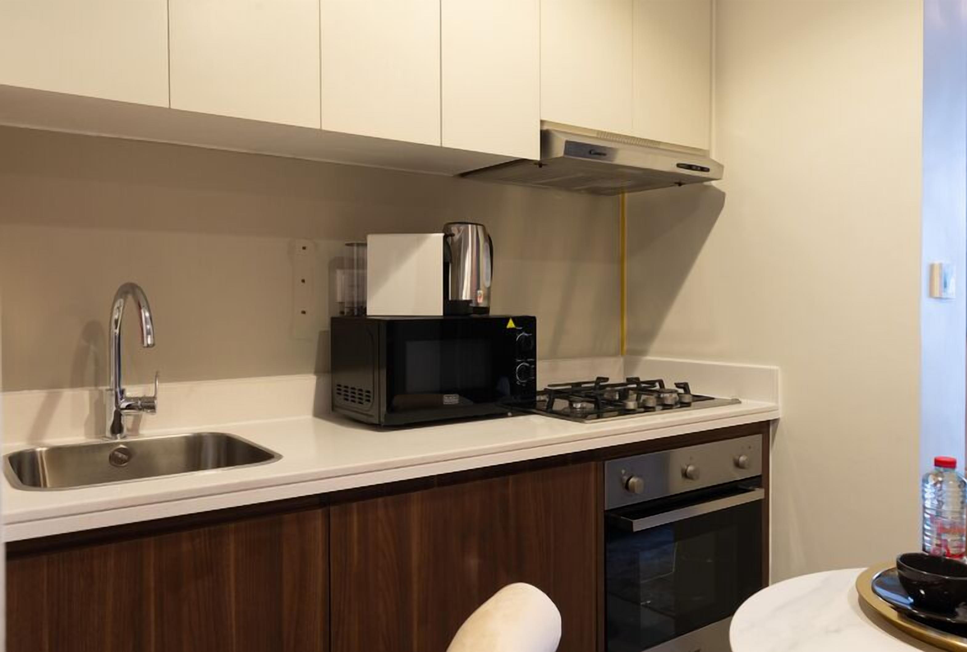 Une cuisine compacte équipée d’un évier, d’un four à micro-ondes, d’une cuisinière et d’un petit four.