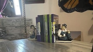 A room with a wooden table, a stack of books, a small figurine, and a lamp. - Ortigiadeluxe S.A.L. (Siracusa)
