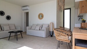 A modern living room with a sofa, a coffee table, a wicker chair, and a dining table. - Alpha VIlla | S Cave Villas Seaside Karystos (Karystos)