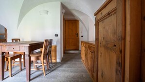 A dining area with a wooden table and chairs, a wooden cabinet, and a door leading to another room. - Pedranzini 23 in Bormio (Bormio)