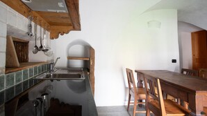 A kitchen with a wooden table and chairs, a sink, and hanging utensils. - Pedranzini 23 in Bormio (Bormio)