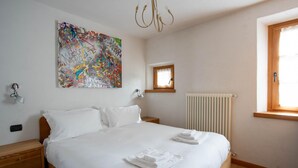 A bedroom with a large bed, a ceiling light, a radiator, and a window with a view. - Pedranzini 23 in Bormio (Bormio)
