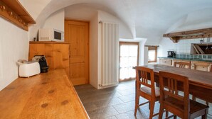 A kitchen with wooden cabinets, a wooden table, and a microwave. - Pedranzini 23 in Bormio (Bormio)