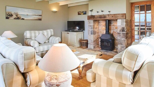 A cozy living room with striped sofas, a fireplace, and a television. - Host Stay The Coach House (Berwick-upon-Tweed)