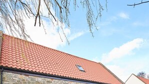 A stone house with a red-tiled roof, large windows, and a front door. - Host Stay The Coach House (Berwick-upon-Tweed)