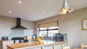 A modern kitchen with a central island, wooden chairs, and a dining table. - Host Stay The Coach House (Berwick-upon-Tweed)