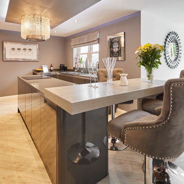 A modern kitchen with a central island, stainless steel appliances, and a pendant light. - Host Stay Casa Feliz (Hull)