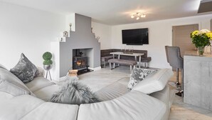 A modern living room with a fireplace, a dining area, and a seating arrangement. - Host Stay Casa Feliz (Hull)
