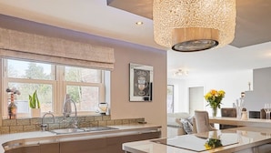 A modern kitchen with a large island, stainless steel appliances, and a hanging light fixture. - Host Stay Casa Feliz (Hull)