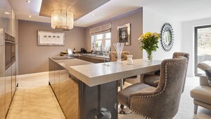 A modern kitchen with a central island, bar stools, and a pendant light. - Host Stay Casa Feliz (Hull)