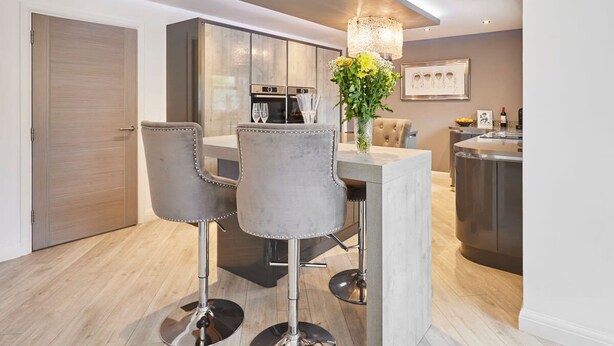 A modern kitchen with a central island, bar stools, and a chandelier. - Host Stay Casa Feliz (Hull)
