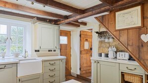 A kitchen with white cabinets, a wooden table, and a wooden staircase.