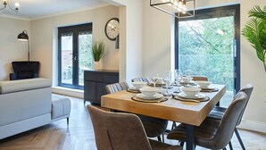 A modern dining area with a wooden table set for four, surrounded by upholstered chairs. - Host Stay Roseberry Topping Townhouse (Middlesbrough)