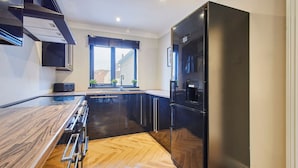A modern kitchen with a wooden countertop, stainless steel appliances, and a herringbone floor pattern. - Host Stay Roseberry Topping Townhouse (Middlesbrough)