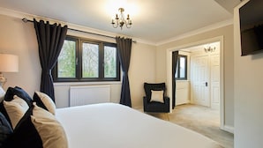 A bedroom with a large bed, a chair, a window with curtains, a radiator, and a television on the wall. - Host Stay Roseberry Topping Townhouse (Middlesbrough)
