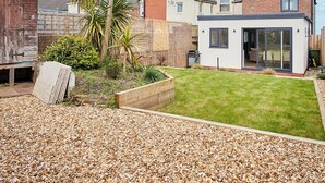 A residential backyard with a lawn, a palm tree, and a modern house with a glass door. - Host Stay Emilyn House (Sunderland)