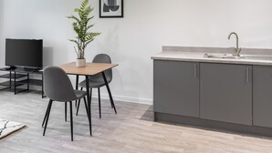 A modern kitchen with grey cabinets, a wooden dining table, and a potted plant. - Host Stay 36 Waterside Place (Taunton)