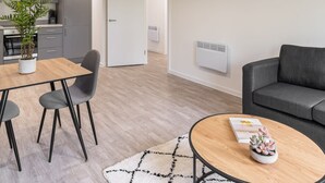 A modern living space with a dining area, a sofa, and a kitchen in the background. - Host Stay 36 Waterside Place (Taunton)
