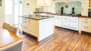 Een moderne keuken met witte kasten, een centraal eiland en een houten vloer.