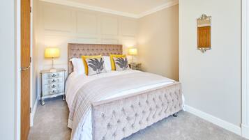 A bedroom with a large bed, two bedside tables, a wooden headboard, and a mirror on the wall.