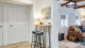 Un vaste espace de vie doté d’un plafond en bois, d’un canapé, d’une table basse et d’un tabouret de bar.
