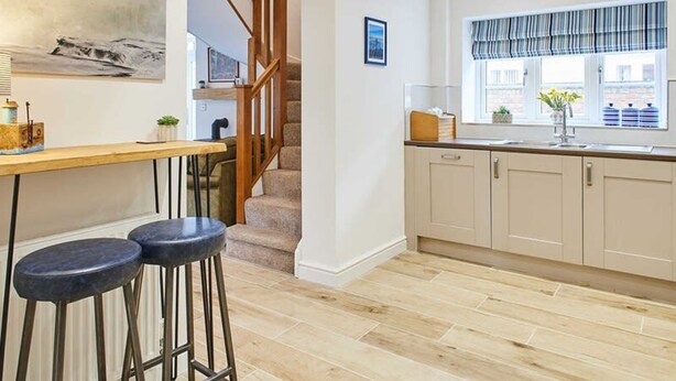 Une cuisine avec un plancher en bois, un escalier en bois et une fenêtre avec des rideaux.